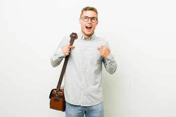 Young caucasian business man surprised pointing with finger, smiling broadly.