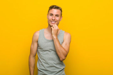 Young caucasian sport man smiling happy and confident, touching chin with hand.