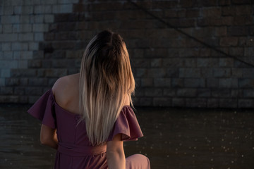 A young, beautiful and slender girl rides on the Amur river. Looking at the big bridge across the river.