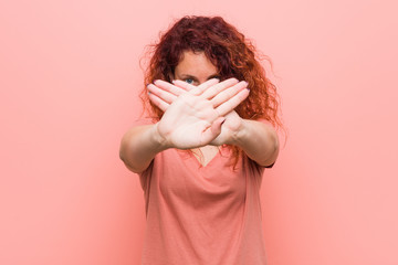 Young natural and authentic redhead woman doing a denial gesture