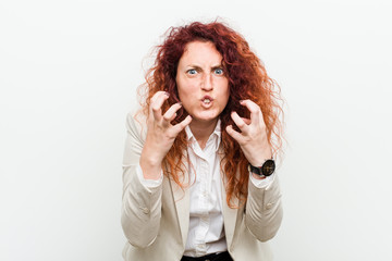 Young natural redhead business woman isolated against white background upset screaming with tense hands.