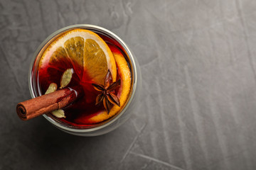 Glass with mulled wine on grey table, top view. Space for text