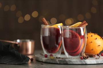 Glasses of tasty mulled wine on grey table against festive lights