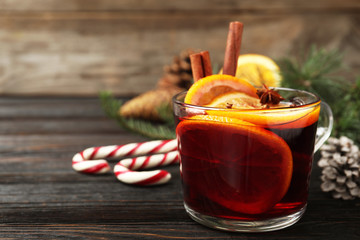 Glass cup of tasty mulled wine on black wooden table. Space for text