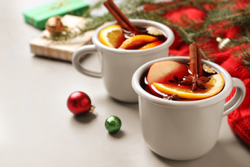 Cups of tasty mulled wine on grey table. Space for text