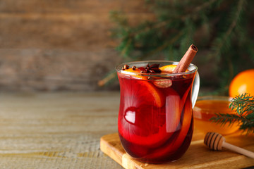Glass cup of tasty mulled wine on wooden table. Space for text
