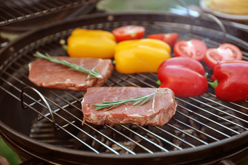 Fresh steaks and vegetables on barbecue grill, closeup