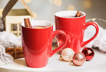 Cups of hot winter drink and Christmas decoration on table against blurred background