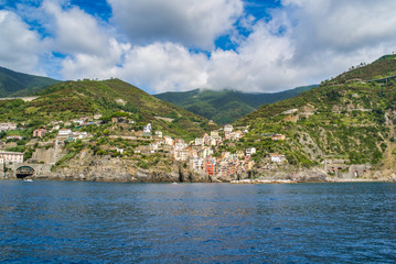 Fototapeta na wymiar Riomaggiore, Cinque Terre, Italy - August 17, 2019: Village by the sea bay, colorful houses on the rocky coast. Nature reserve resort popular in Europe