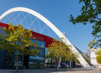View of Lanxess Arena, indoor multifunction arena, with glass facade and red aluminium cladding,...