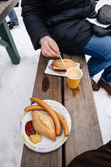 Woman eating traditional German wurst sausage and traditional meat drinking a hot coffee while visiting the snow mountain resort