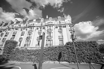 Black and white image of low wide angle view of Parisian property apartment building with French balconies and clear sky with some scattered clouds