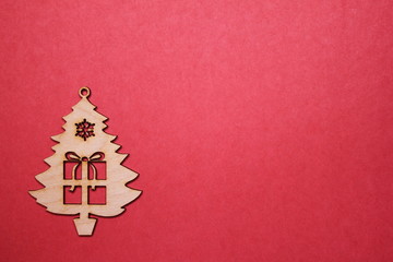 Wooden Christmas tree figurine with a gift on a red background. Copy space.