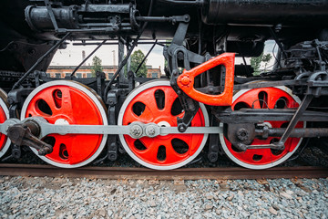 Red wheels of old black steam locomotive, close up