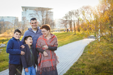 Portrait of happy adult married couple with two boys at sunset in the park in selective focus.