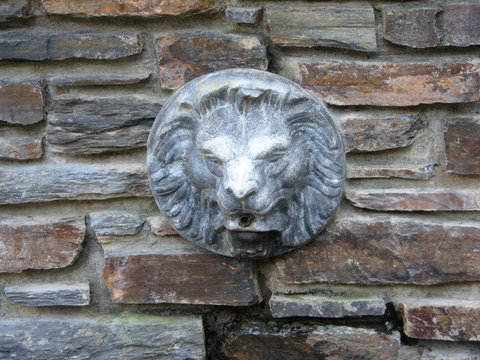 Lion head outdoor fountain ornament on a stone brick wall