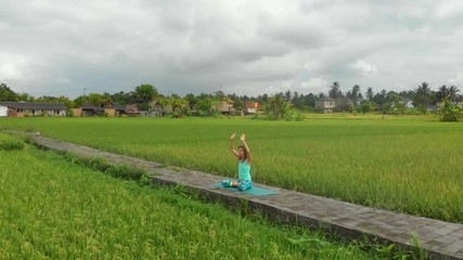 Slowmotion aerial shot of a young woman doing meditation for Muladhara chakra in a Balinese way