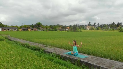 Slowmotion aerial shot of a young woman doing meditation for Muladhara chakra in a Balinese way