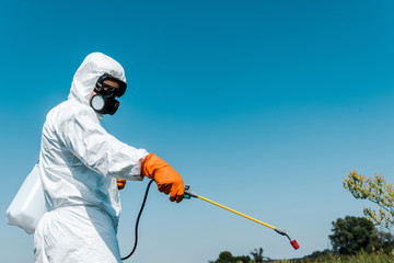 exterminator in protective uniform holding toxic spray outside - obrazy, fototapety, plakaty