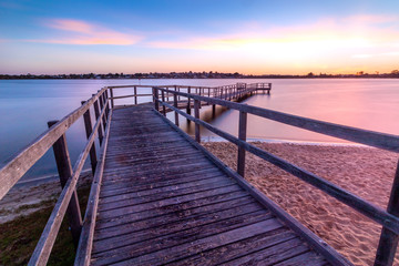 Long exposure photo of a pier on sunset in the evening with a colourful sky and clouds