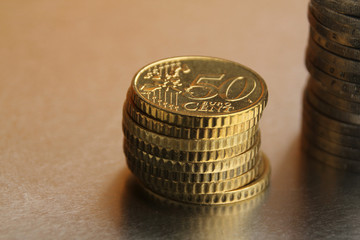 metal coins of 50 cents EU are stacked on a yellow background, financial concept, close-up, copy space