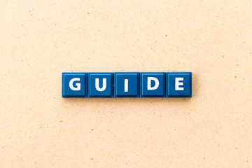 Tile letter in word guide on wood background