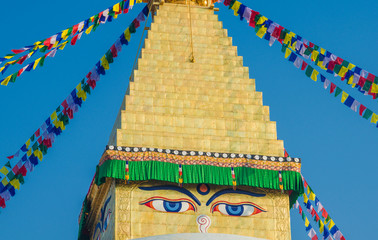 The dome and gold spire of Bodhnath Stupa, Kathmandu, Nepal, with Buddhist prayer flags.
