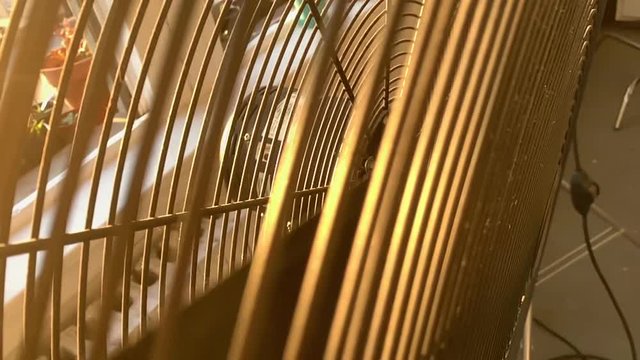 Slow motion video of inner workings of a dangerous metal fan including turning blades.