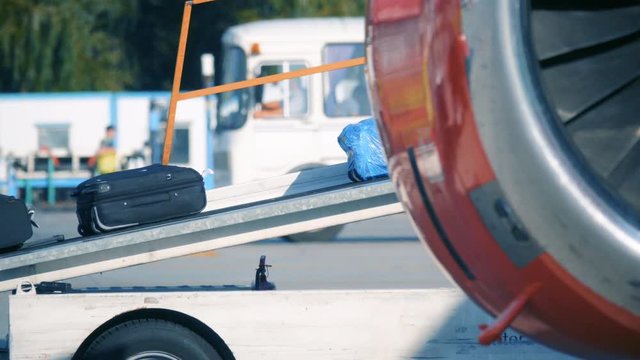 Luggage - suitcases and bags travel along the baggage tape from an airplane to a cargo car to be sent to the airport terminal.