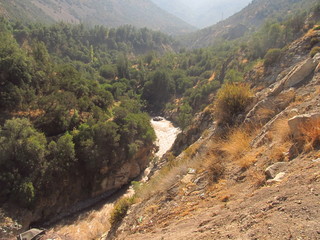 a river with brown water running among the mountains in Cajon del Maipo, Chile
