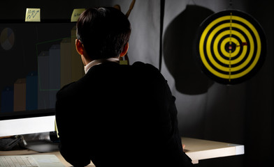 Tomboy Manager CEO looks at Dartboard and hold dart to throw as it is Growth of Business to achieve...