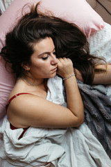 Fototapeta premium Pensive and attractive sad woman lying on the bed. Thinking about problems. Feeling worried, hurt, heartbroken lonely