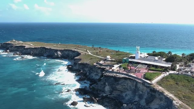 Aerial view of the far side of isla mujeres whith the sea hilling the cliffs. Orbiting around.