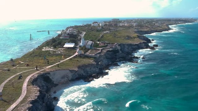Aerial view of the far side of isla mujeres whith the sea hilling the cliffs. Moving forward.