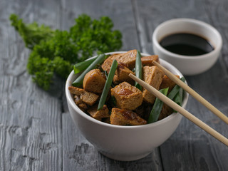 Fried tofu, parsley and wooden sticks on the table.