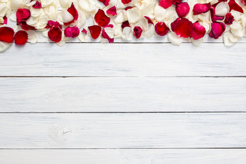 Red and white rose petals border on a white wooden background. Place for text. Top view. Love concept.