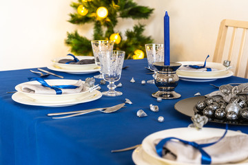 Blue christmas table setting with christmas tree in background