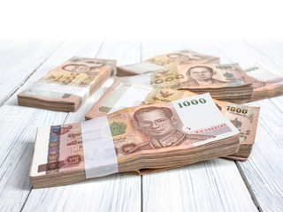 Wad of Thai banknotes on white wooden background. Kind of thousand Thai baht. Money concept.