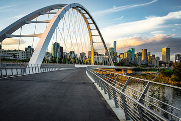 Edmonton, Alberta, Canada skyline at dusk with suspension bridge in foreground and clouds 