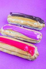 multi-colored french eclairs with fruit filling on a purple background