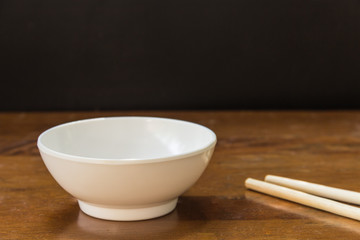 white bowl and wooden chopsticks on wood floor