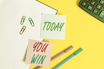 Text sign showing You Win. Business photo showcasing be first in school race or competition Got gold medal Rating Empty blue paper with copy space paper clips and pencils on the yellow table
