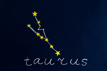 constellation Taurus drawn in chalk and gold stars on a chalkboard looking like a night starry sky