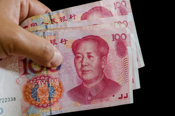 Chinese money in hand on a black background. Yuan close up.