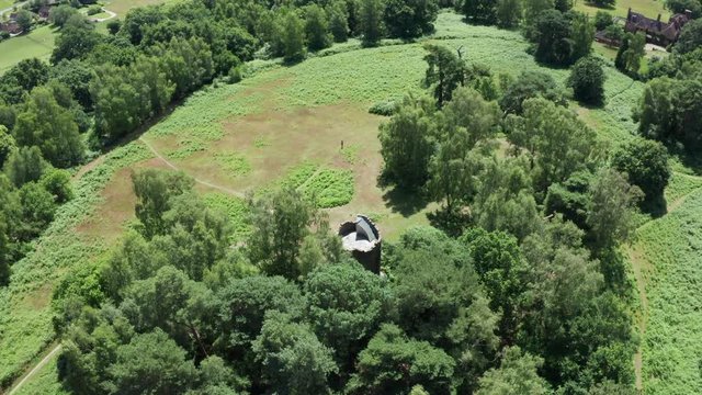 An aerial shot circuling an old folly tower in the English countryside, keeping the folly in shot.