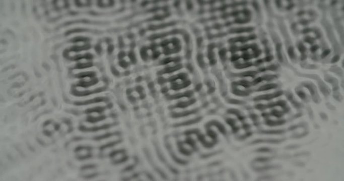Rhythmic shapes on water surface through different frequencies. Static close up shot.