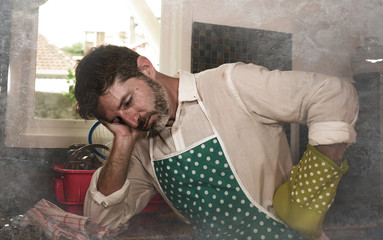 dramatic grunge portrait of 30s to 40s house husband or single man in kitchen apron doing domestic chores washing dishes or cooking in stress feeling frustrated