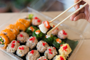 Mix japanese sushi rolls in take away package.