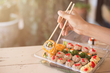 Mix japanese sushi rolls in take away package.