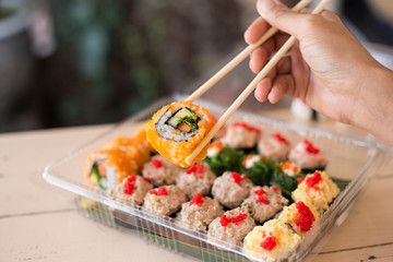 Mix japanese sushi rolls in take away package.